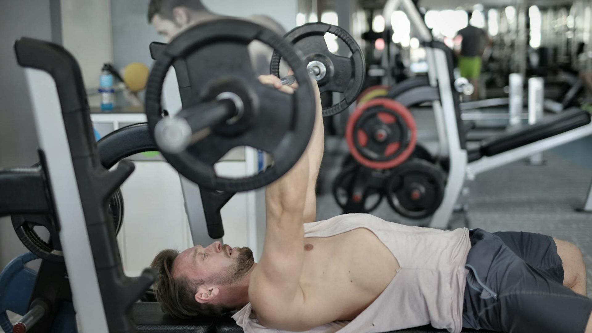 Man in a focused strength training pose in a minimalist gym.